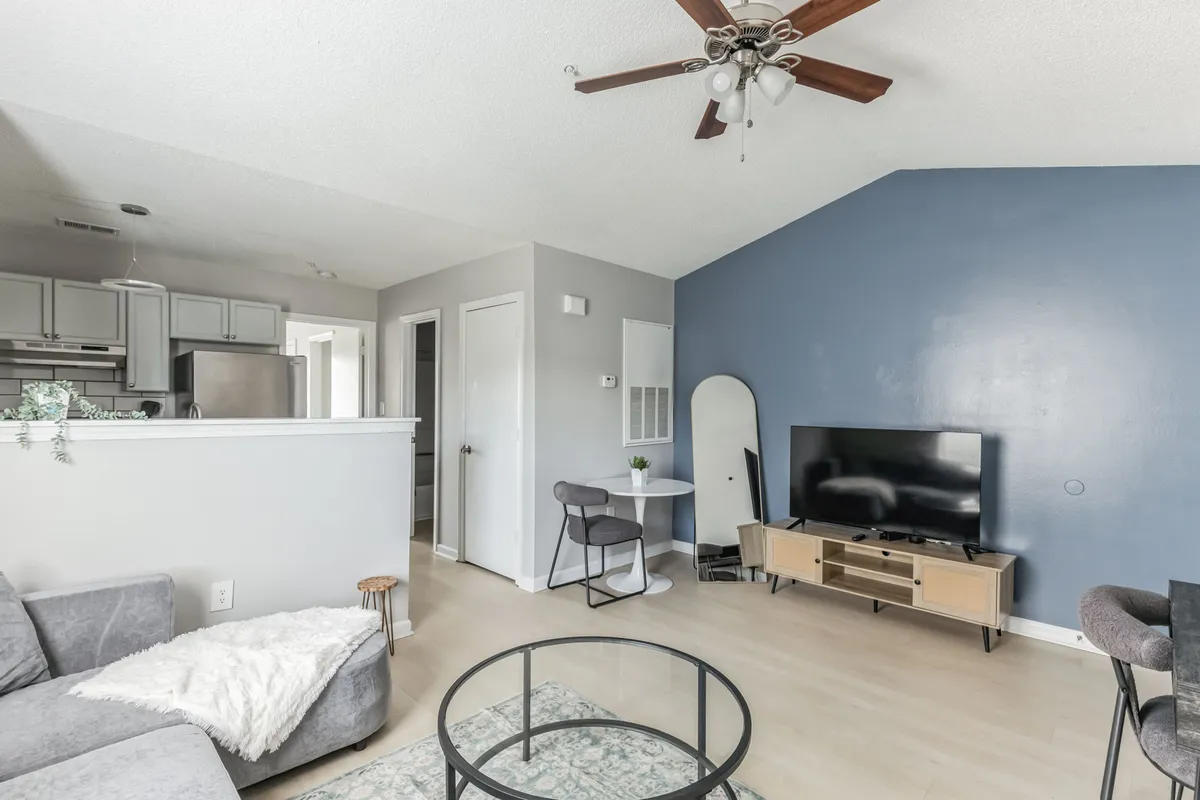 This photo highlights a modern living room setup with a plush sofa, a sleek TV stand, coffee table, and a decorative plant. The arrangement invites relaxation and entertainment, signaling a space designed for watching movies, casual gatherings, or quiet evenings in.