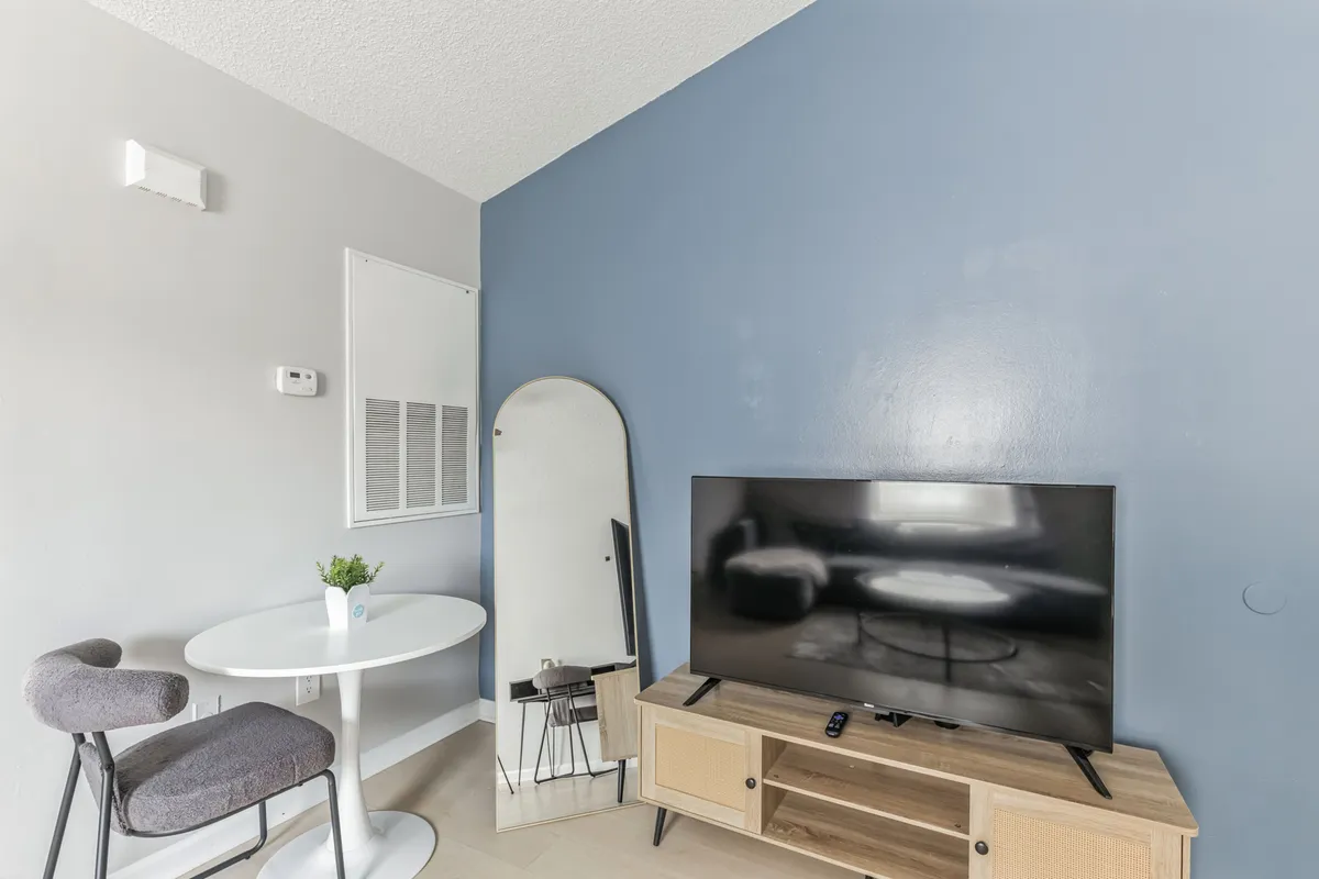 This interior shot reveals a stylish living area with a cozy dining table, television, and accent wall. The atmosphere feels intimate and modern, perfect for enjoying a movie night or an intimate dinner for two after a day exploring the town.
