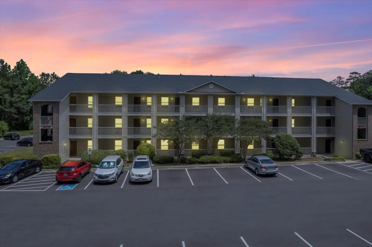 This image captures the exterior of the apartment building at sunset, with balconies visible and a tranquil atmosphere. The warm hues of the sunset provide a romantic backdrop, while the building and its surroundings exude a calm, inviting vibe—ideal for unwinding after an evening out.