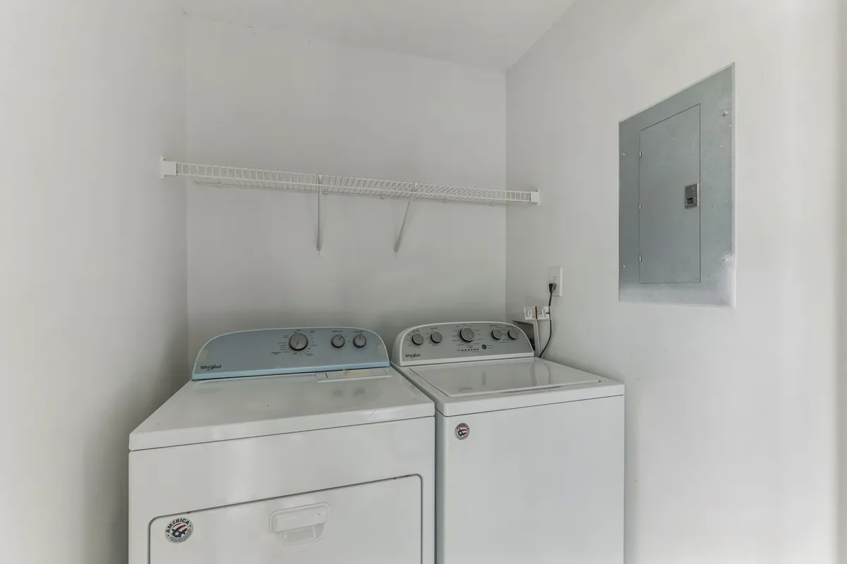 A practical laundry area equipped with a washing machine and dryer, complemented by a shelf overhead for storing cleaning supplies. The space is organized, efficient, and ready for tackling laundry needs during your stay.